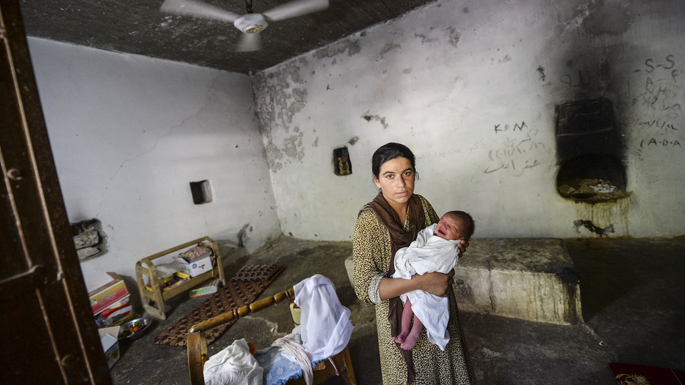 An unnamed Yazidi woman who escaped abuse from ISIS holds her baby in a refugee camp in Lalesh, Iraq.