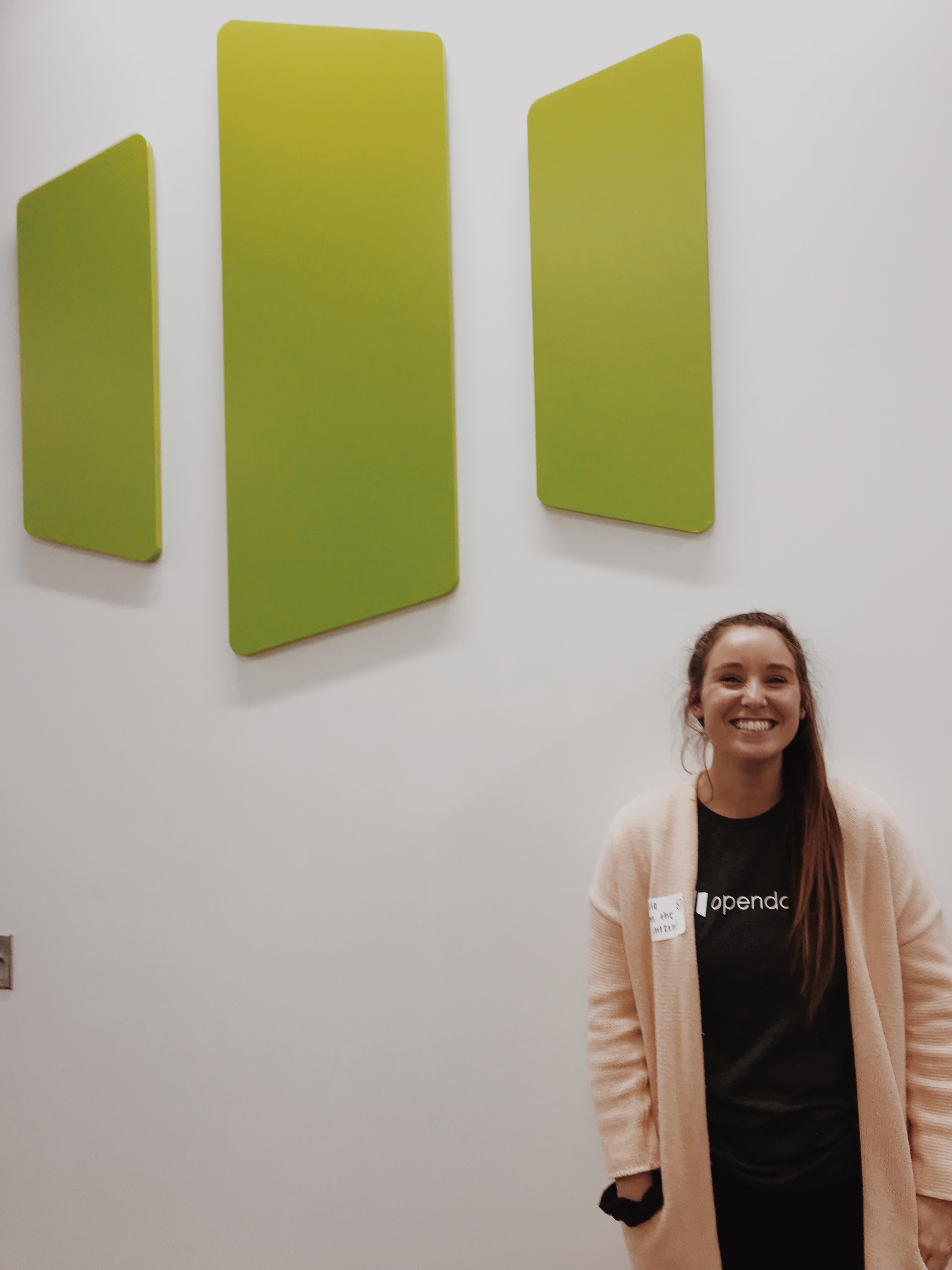 CoJMC senior Paige Stanard smiles in front of the Opendorse logo on her first day as an intern at the office headquarters in Lincoln.