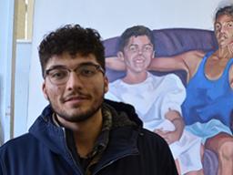 Luis Martinez stands in front of his painting titled “Flojeando,” in the Richards Hall painting studio.