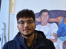 Luis Martinez stands in front of his painting titled “Flojeando,” in the Richards Hall painting studio.