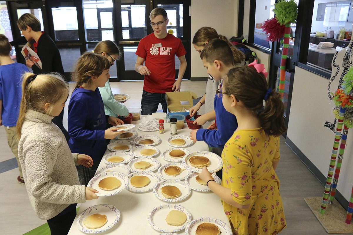 A teen ambassador helps Malcolm fourth-grade students prepare oatmeal pancakes with fruit instead of syrup. (Photo by Vicki Jedlicka, Nebraska Extension in Lancaster County)