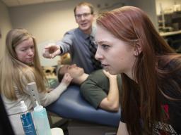 Nebraska students Madison Burger and Allison Porter work with Greg Bashford as part of a UCARE project in 2016. Part of the work, shown here, included using a device that measures brain waves through eyelid pressure.
