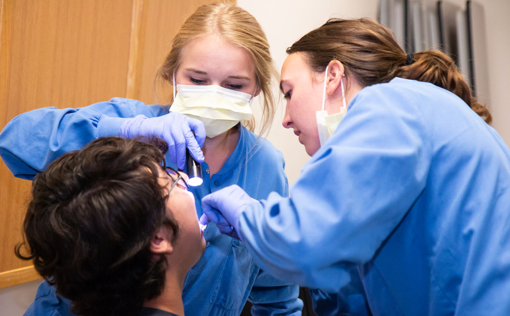 Patient Oscar Kaled Gonzales gets a checkup from Nebraska College of Dentistry students Maddi McConnaughhay and Olivia Straka at Lincoln's El Centro de las Américas.