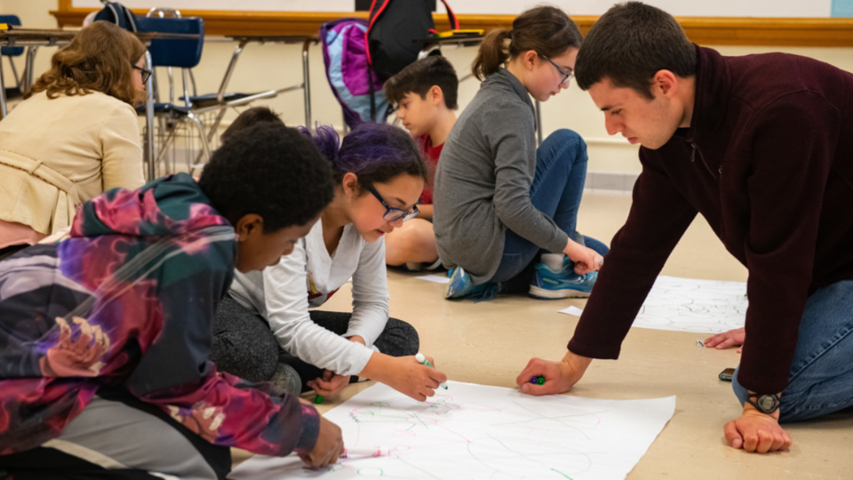 Luke Novak works with children as part of  Dr. Julia McQuillan's research on science knowledge/interest among middle schoolers.