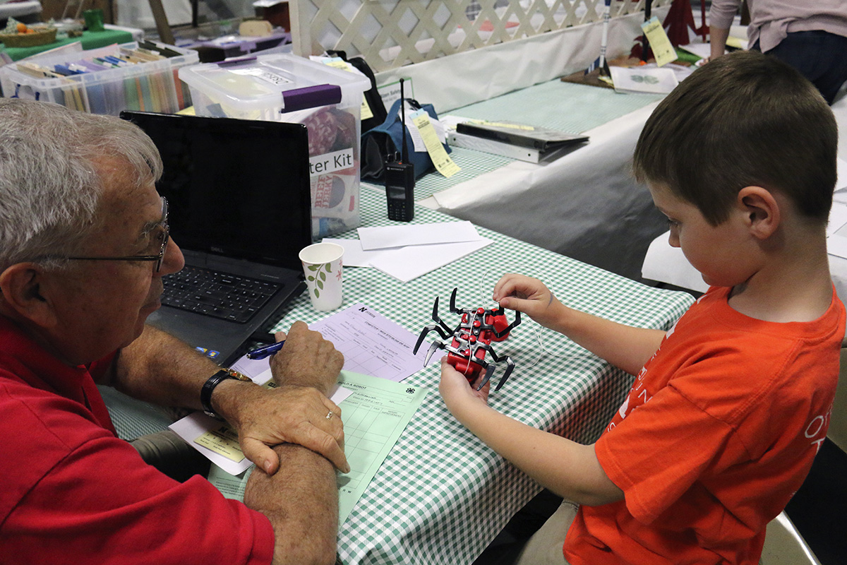 Pictured is a youth discussing his kit-labeled robot with a judge.