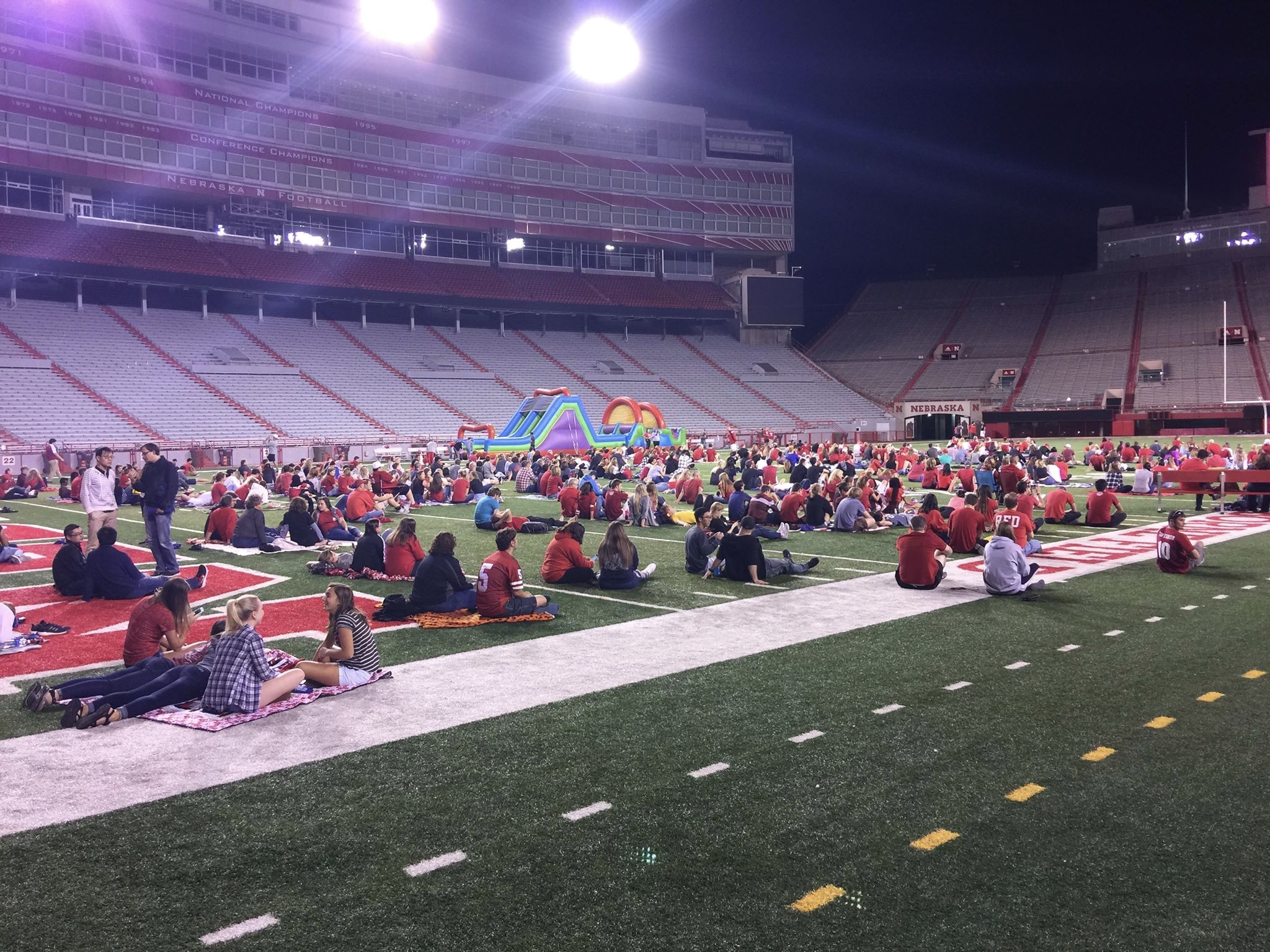 Students and family members watch a football game on the big screen in Memorial Stadium.
