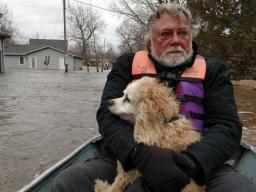Craig Sorensen holds onto his dog, Ollie, as they are evacuated from their home near Bellwood last spring.  (Julie Sorensen, courtesy photo)