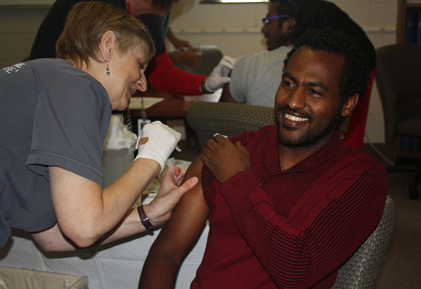 A student rolls up their sleeve to receive a free flu shot.