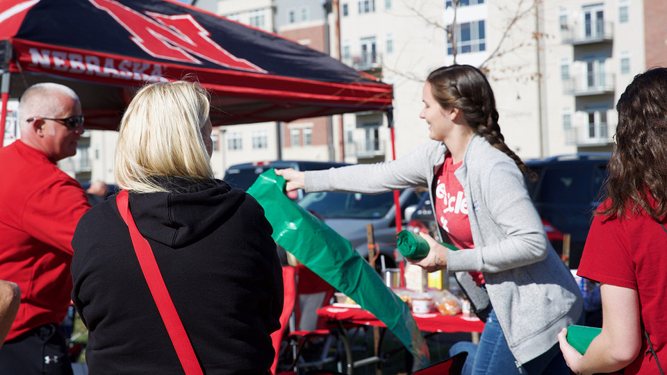Natalie Bielenberg, a volunteer with Go Green for Big Red, hands out green recycling bags at a football tailgate Oct. 26.