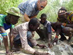 Matthew Douglass, assistant professor of practice in the College of Agricultural Sciences and Natural Resources, (standing) works with Daasanach men to mark out pasture boundaries, watering points and conflict areas on prints of satellite imagery.