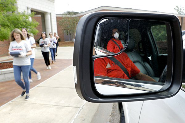 Vijay Patel, reflected in his truck’s side mirror, waits for teachers to deliver iPads for his two children during a curbside pickup at Eastside Elementary, in Clinton, Miss. —Julio Cortez/AP
