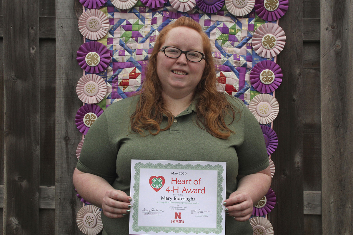 Pictured behind Mary is her senior year 4-H project, a quilt made of all her 4-H ribbons.