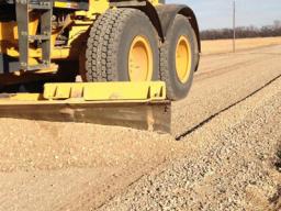 Close-up of motor grader at work grading a road