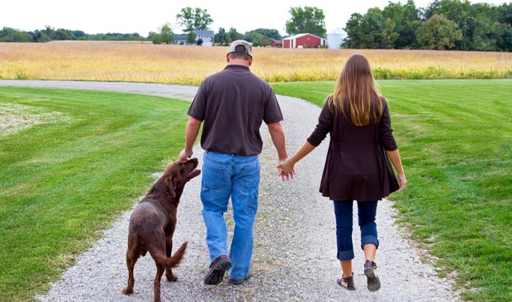Man and woman walking with dog down a path.