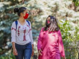 Asmita Jayswal, a junior in computer science (lright), and Esha Mishra, a graduate student in physics, walk along R Street wearing the new N face mask. More than 60,000 face masks will be distributed to all students, faculty and staff for the fall semeste