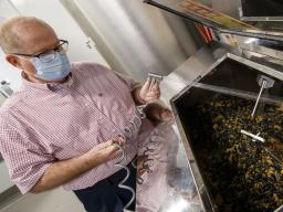 Dave Annis, director of University Dining Services, sprays down food and enzyme pellets in a biodigester in Cather Dining Center. The device can hold up to 400 pounds of food a day. 