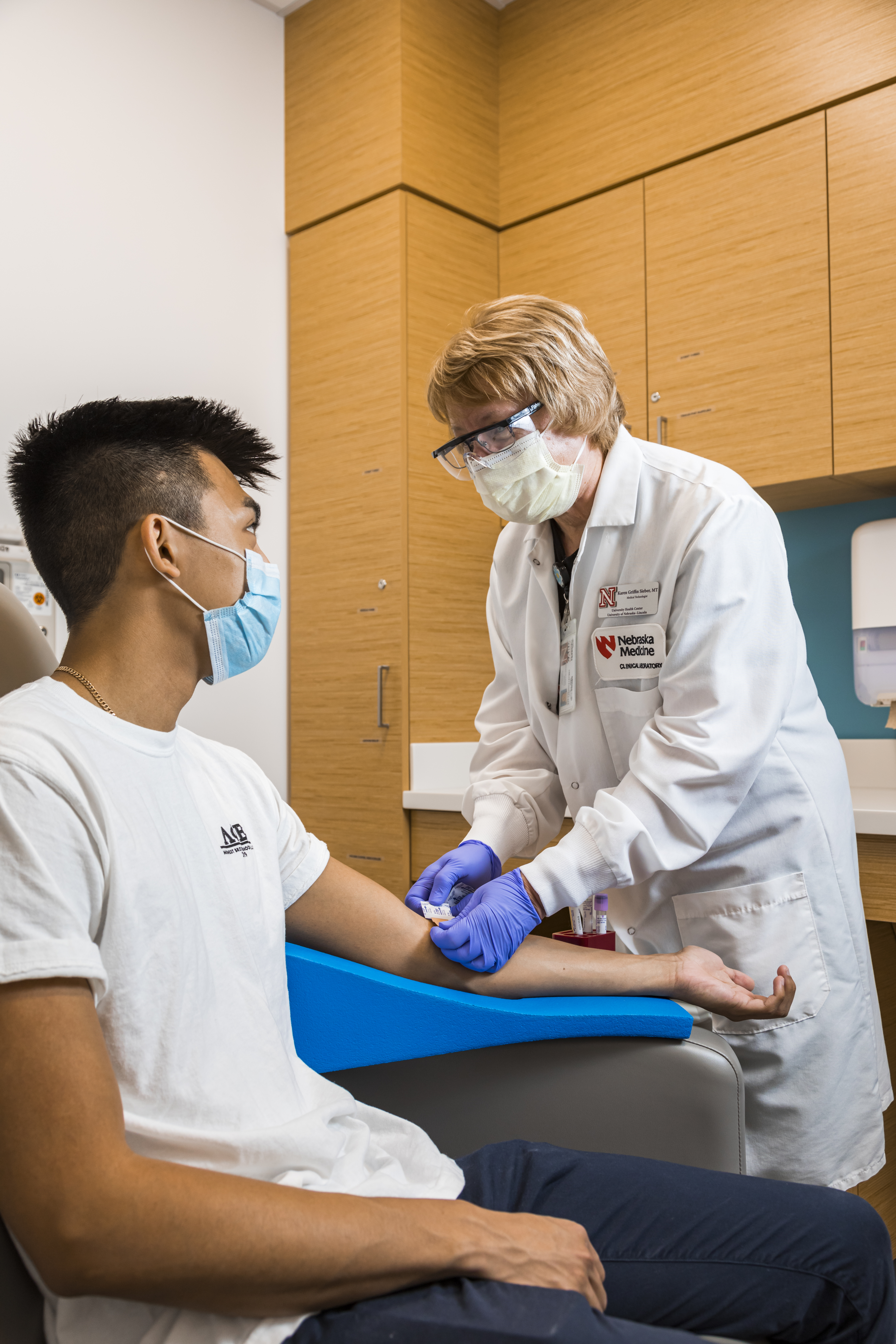 A lab staff member prepares a student for a blood draw.
