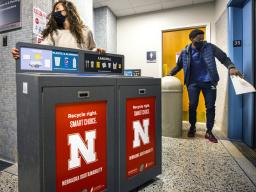 Morgan Hartman, project coordinator for recycling services, wheels a new recycling station down the hallway of Canfield Hall as student worker Damien Niyonshuti loads an old trash can onto an elevator. The Office of Sustainability is installing the new re