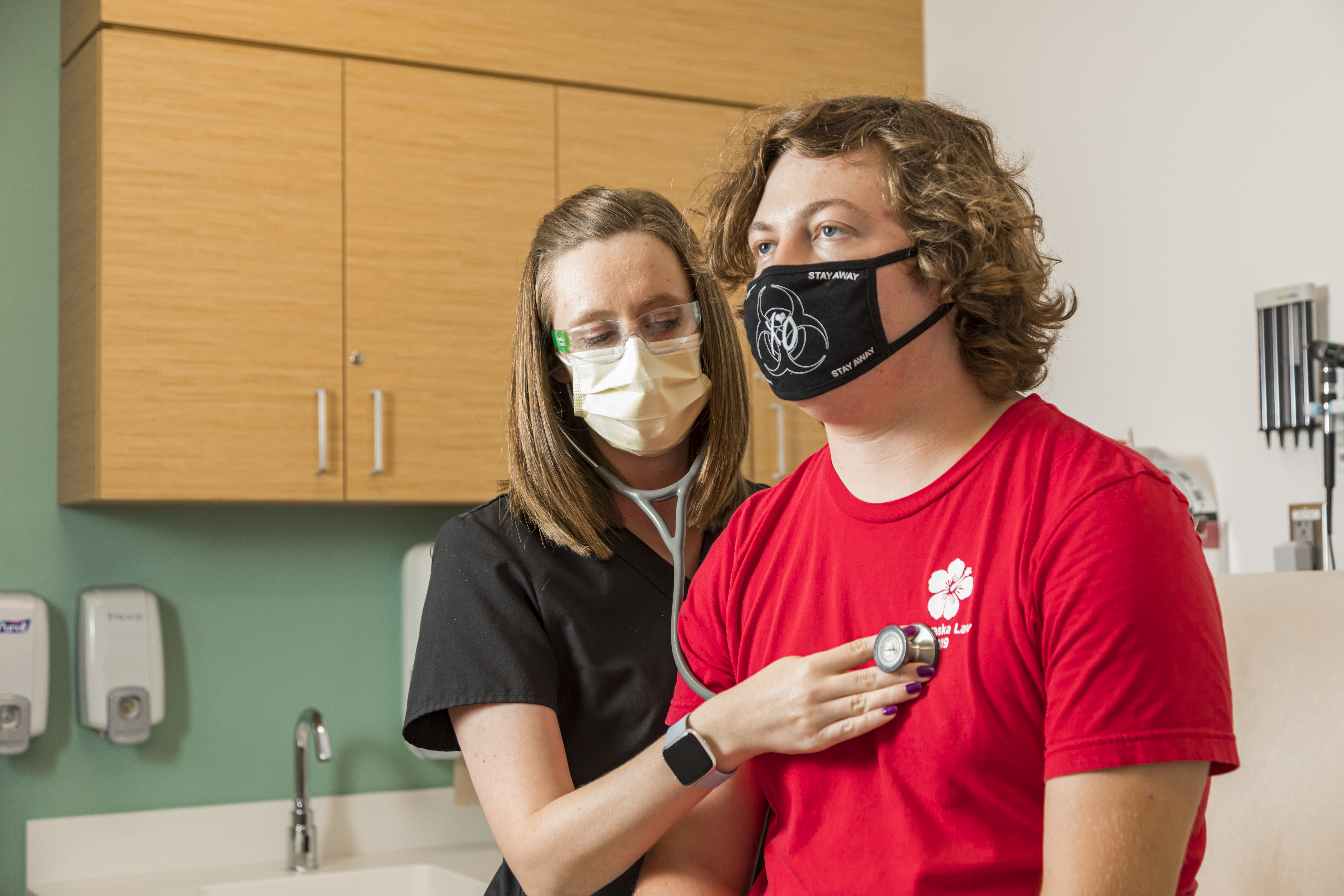 Bethany Berg, PA-C and health care provider at the University Health Center, listens to a student's heartbeat during their medical appointment.