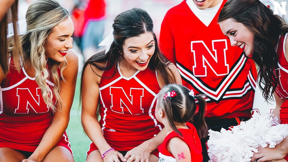 Kaela Meyer (center) interacts with a young fan at a Husker football game, prior to the COVID-19 pandemic.