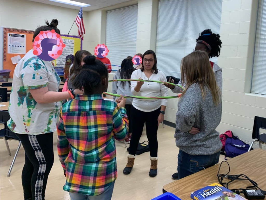 NE STEM 4U mentor Amy Klar and participants use a hula hoop to experiment with network interdependence.