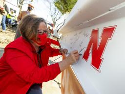 Sherri Jones, dean of the College of Education and Human Sciences, signs the final beam that was lifted into place during the April 9 topping out ceremony. An evergreen tree was also placed atop the beam, signifying the safe completion of the internal str