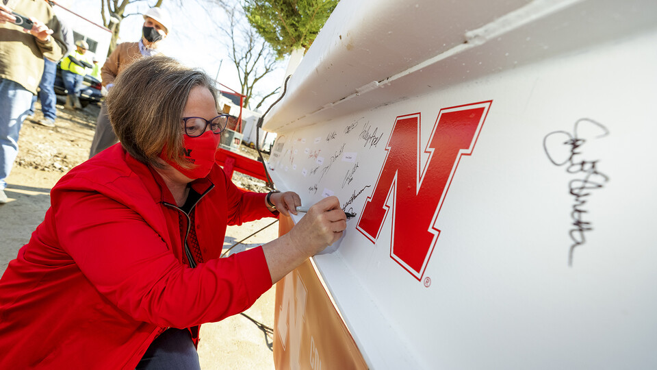 Sheri Jones, dean of the College of Education and Human Sciences, signs the final beam that was lifted into place during the April 9 topping out ceremony. An evergreen tree was also placed atop the beam, signifying the safe completion of the internal stru