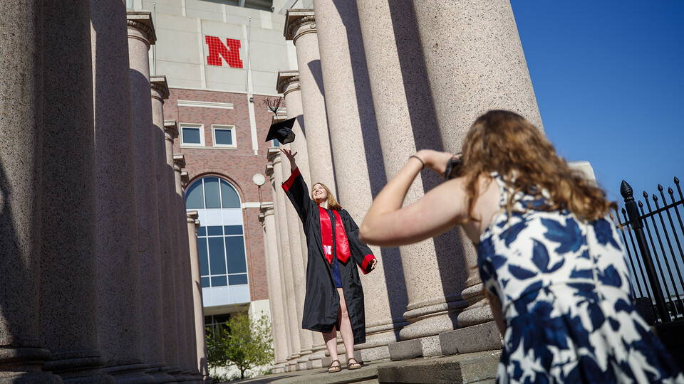 Rose Wehrman (in regalia) and Sarah Schilling prepared for commencement in spring 2020 by shooting photos amongst the Columns by Memorial Stadium. The iconic pillars, which have stood by Memorial Stadium for 86 years, will be on the move this summer as co