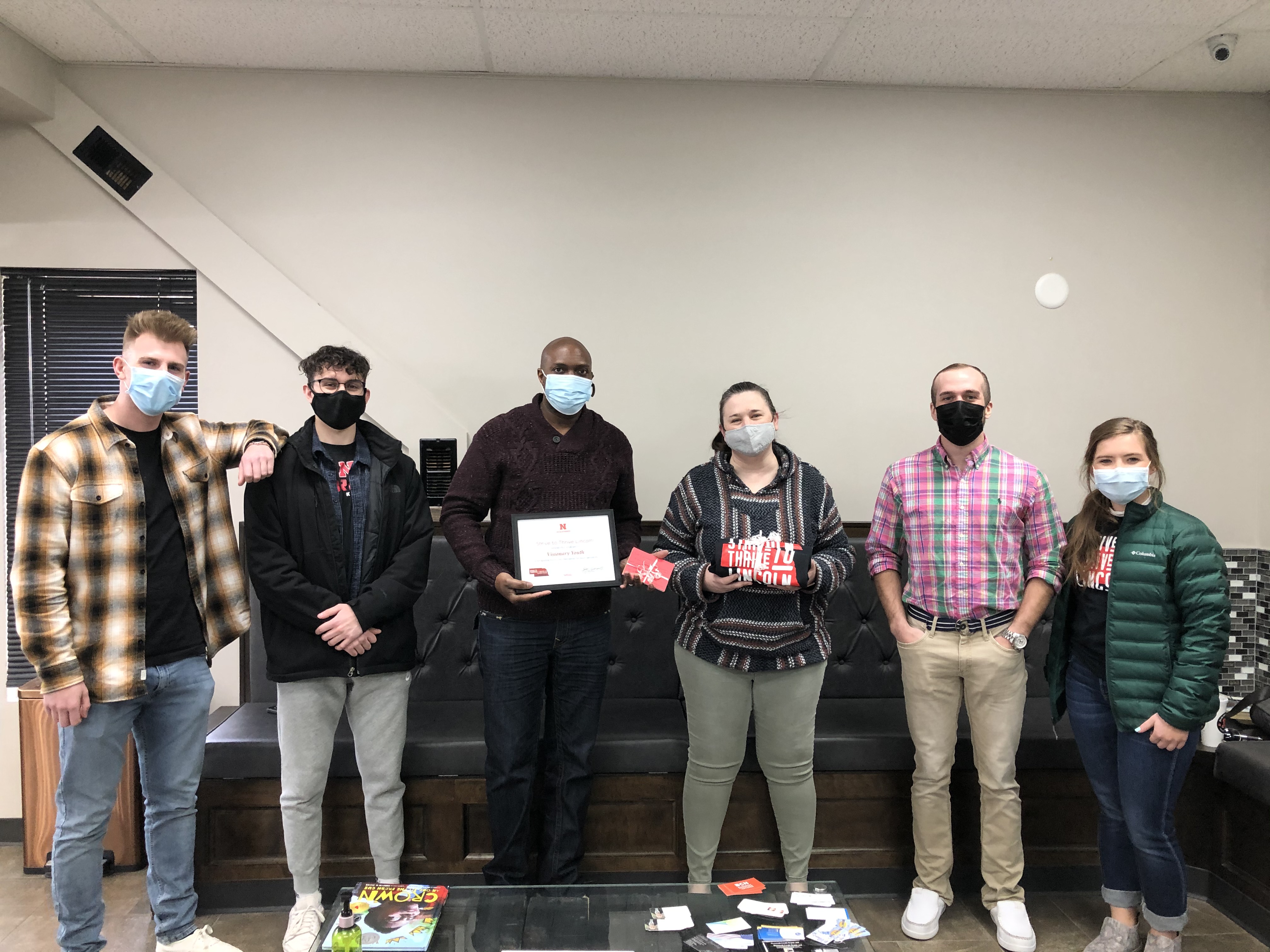 Members of the Awards Ceremony task group present a certificate and shirts to Visionary Youth Founder and Executive Director Kwabena Mensah and Vice President Kris Whisenhunt.