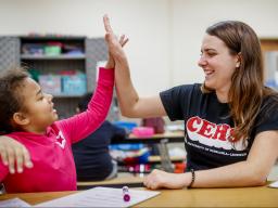 CEHS student high fives elementary aged child during America Reads program