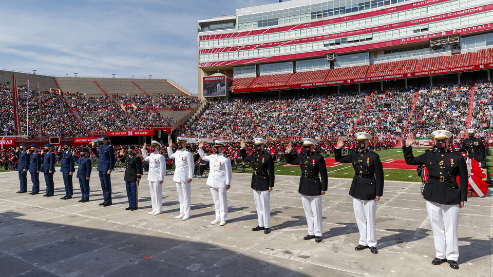 Graduating members of the university's ROTC program stand and receive their commissions during the spring 2021 undergraduate commencement ceremony in Memorial Stadium.