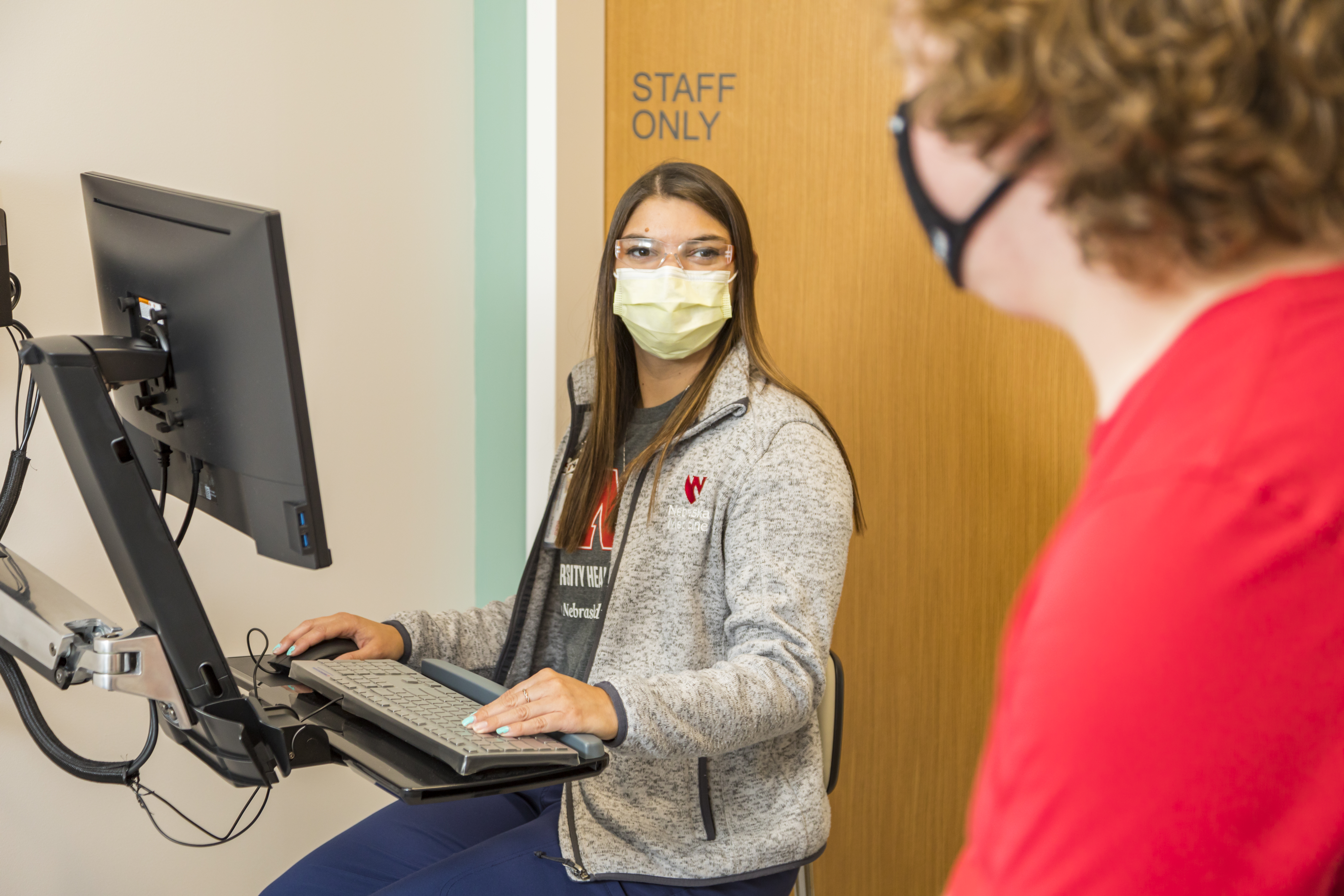 A student talks with a Medical Assistant about their symptoms during their appointment.