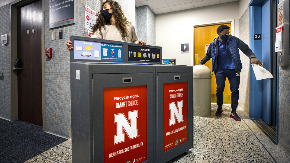 Morgan Hartman, project coordinator for recycling services, wheels a new recycling station down the hallway of Canfield Hall as student worker Damien Niyonshuti loads an old trash can onto an elevator. The changes to aid recycling were done to align with 