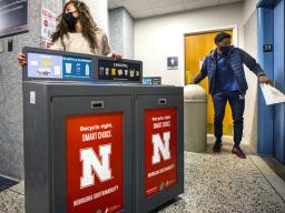Morgan Hartman, project coordinator for recycling services, wheels a new recycling station down the hallway of Canfield Hall as student worker Damien Niyonshuti loads an old trash can onto an elevator. The changes to aid recycling were done to align with 
