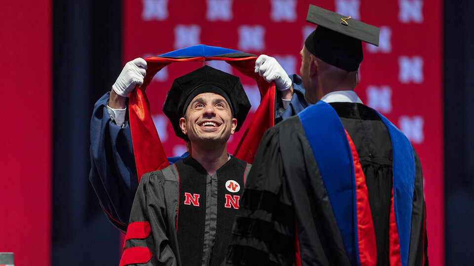 Ali Jamal Mazaltarim watches his doctoral hood being placed over his head during the graduate and professional degree ceremony Aug. 13 at Pinnacle Bank Arena.