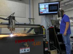 Jerry Reif, shop manager at Nebraska Innovation Studio, watches as a plasma cutter cuts through steel.