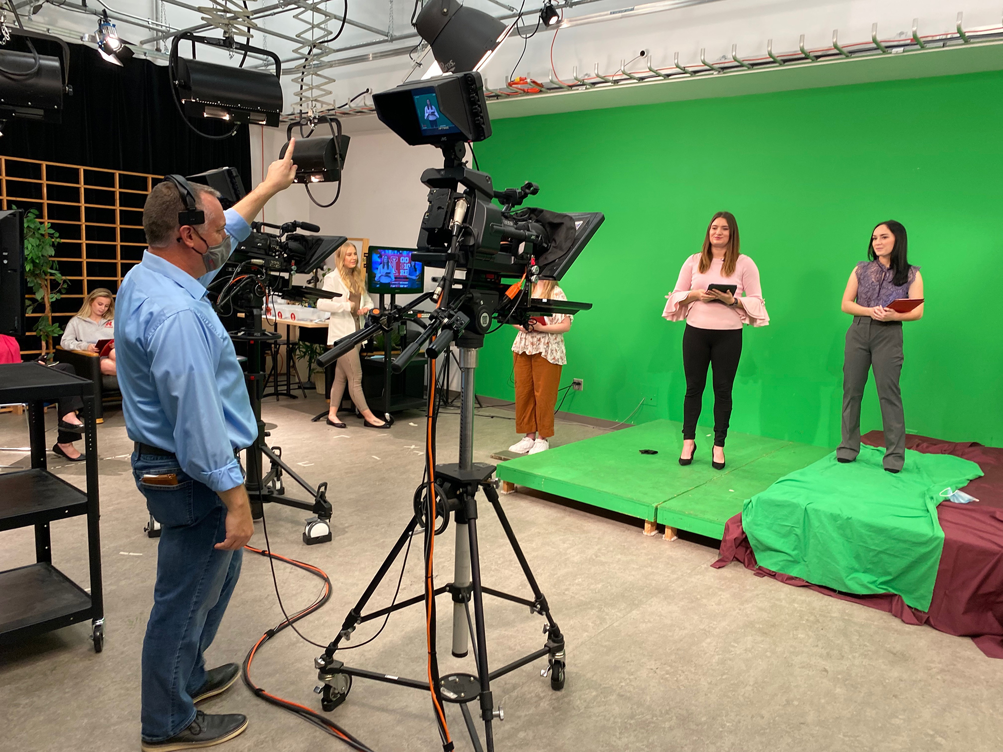 Anchors Kloee Sander, left, and Hallie Gutzwiller prepare for the Nebraska Nightly show open. Faculty liaison Brian Petrotta provides a countdown. [photo: College of Journalism & Mass Communications | University of Nebraska-Lincoln]
