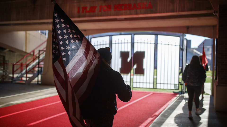 Jerod Post, '13 and a Marine veteran, carries the United States flag into Memorial Stadium to the starting point of the Ruck March, Nov. 14, 2018. [Craig Chandler | University Communication]