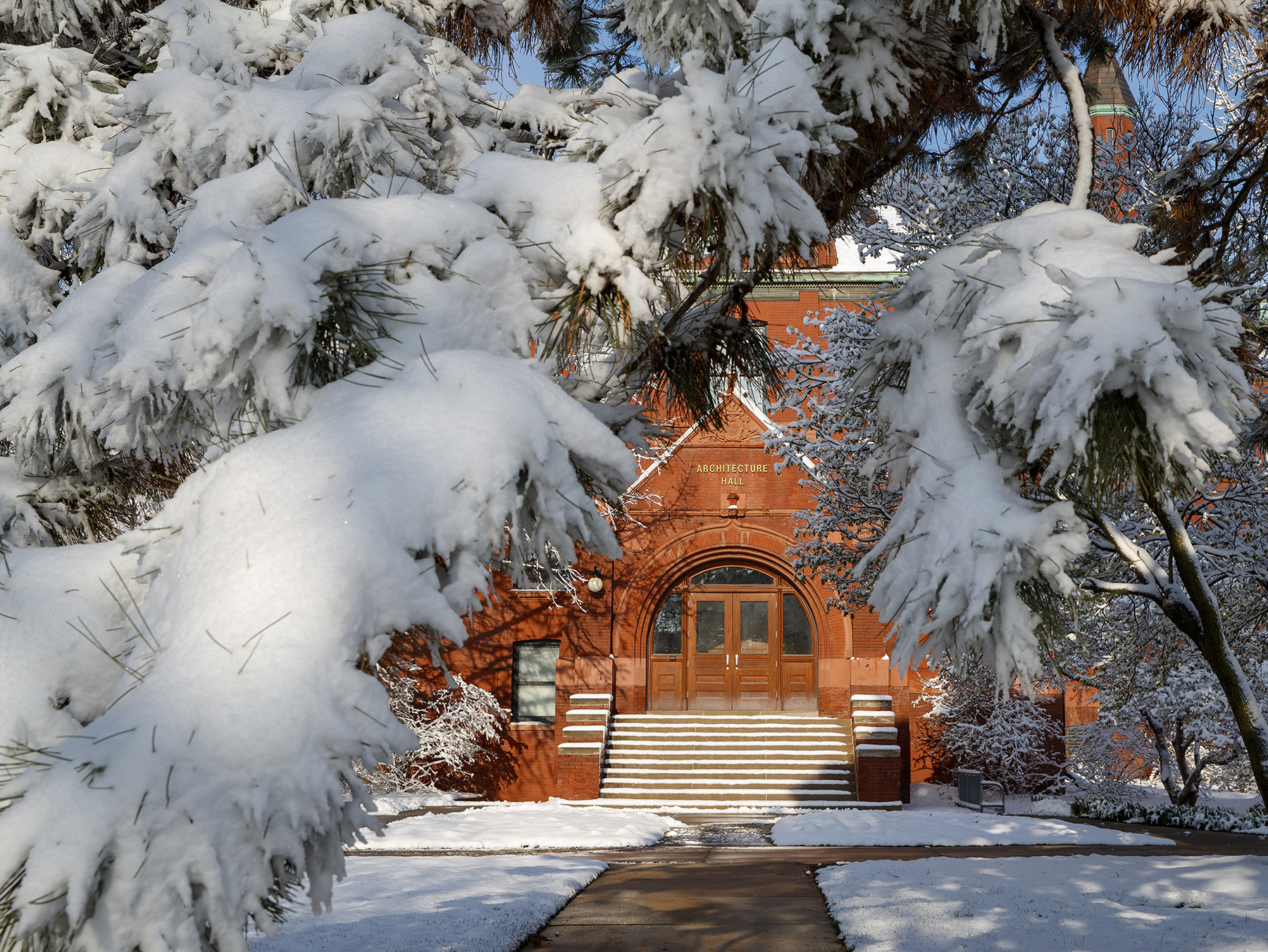 Snow-covered trees frame the entrance to Architecture Hall [University Communication].