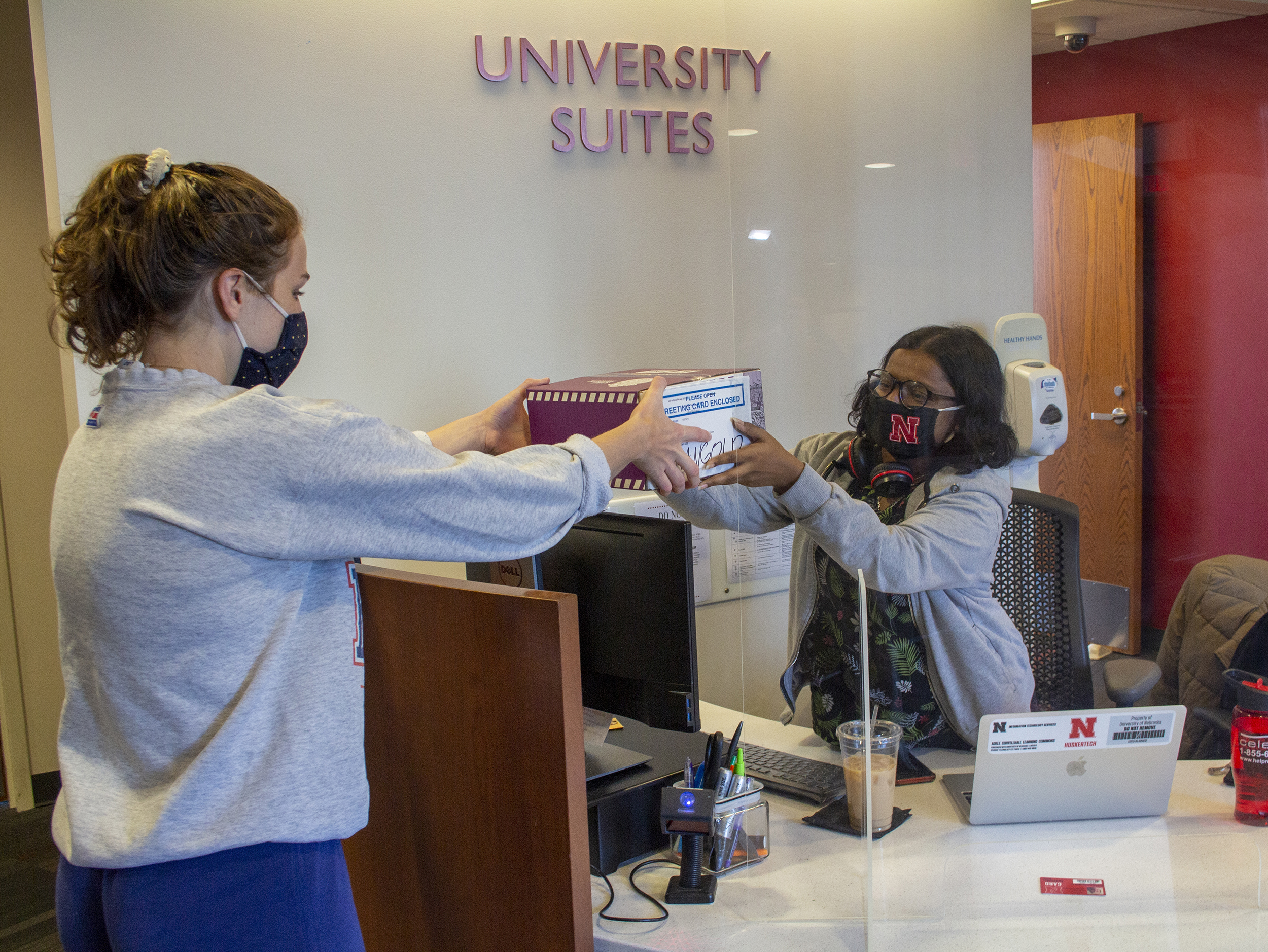 A student desk attendant assists a Husker at the Welcome Desk inside University Suites. [Mike Jackson | Student Affairs]