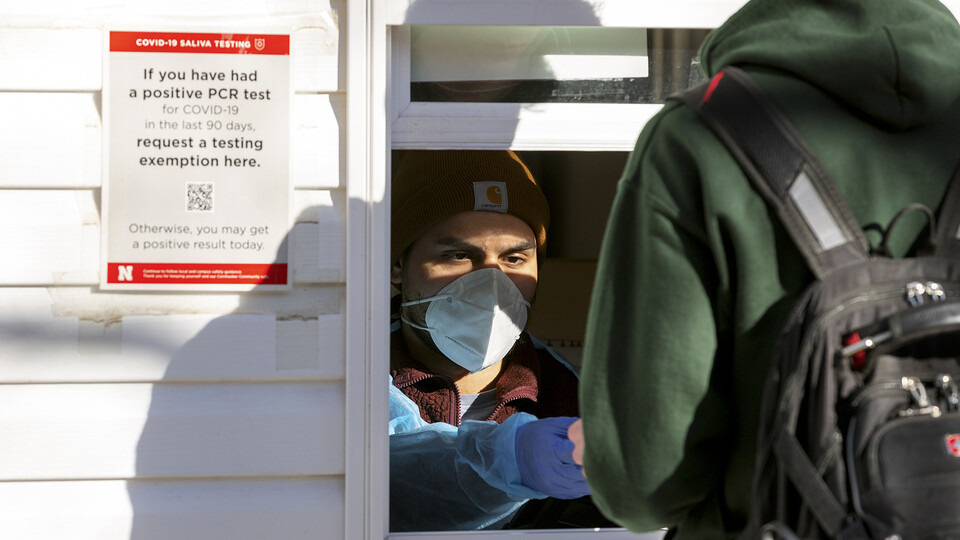 A student delivers a vial of saliva at the Nebraska Union COVID-19 test location on Jan. 18. The university will transition to a random mitigation testing model for all students, faculty and staff (regardless of vaccination status) the week of Jan. 30. [C
