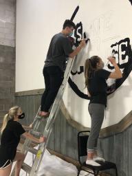 Members of MNGT 411 spend their Friday afternoon painting logos on the walls of The BAY's indoor skatepark.