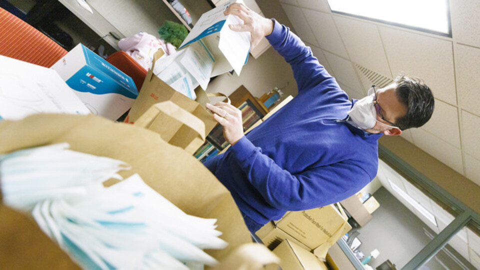 Jon Gayer, assistant director of Fraternity and Sorority Life, sorts masks into bags for distribution on campus.