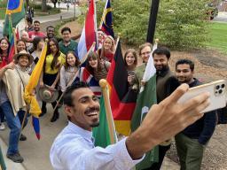 Students gather to take a selfie before marching with their national flags during the 2021 Homecoming Parade. 