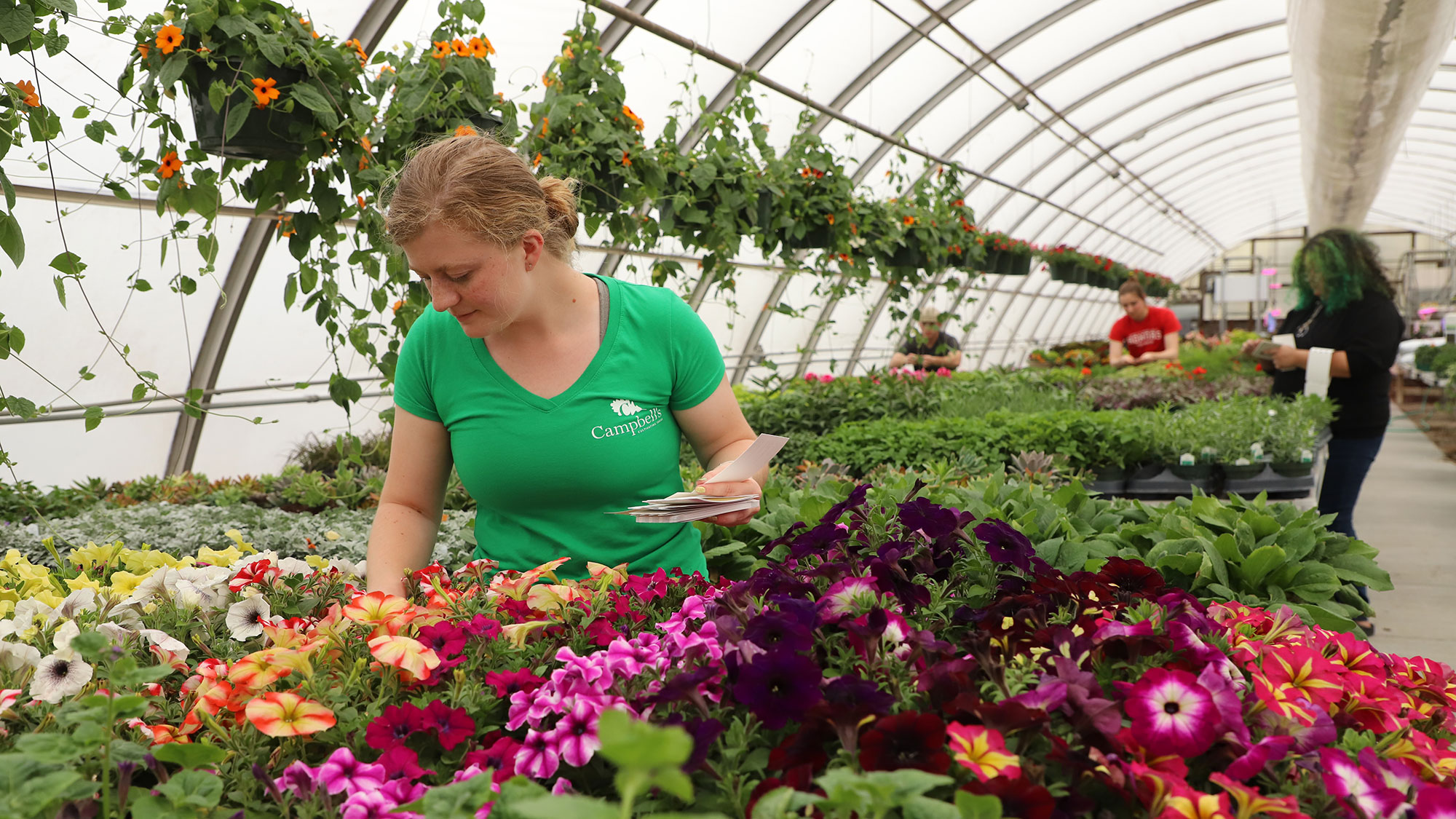 Sarah Wulf, Horticulture Club president, and club members tag plants in the greenhouse in preparation for the club’s sale May 4–6.