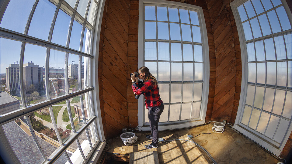 Erin Colonna, graphic designer with the University Libraries, documents signatures on the walls inside the Love Library cupola. A summer restoration will repair damage to the exterior of the cupola. [Craig Chandler | University Communication]