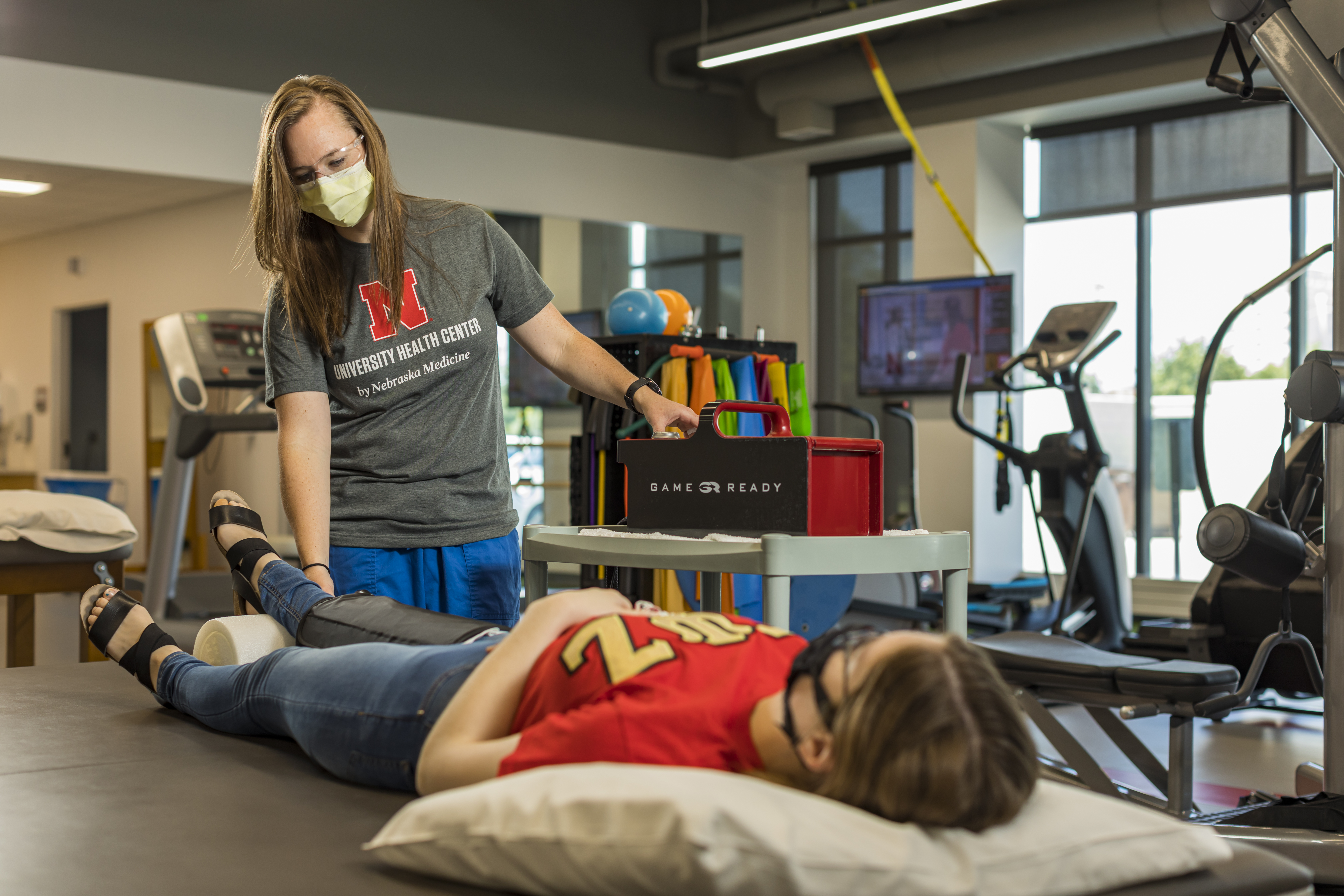 Physical Therapist Kelsey Gaston guides a student through a leg stretch.