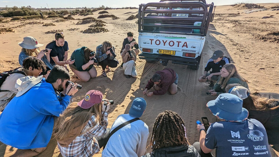 Huskers on a study abroad experience in Namibia gather round to study a shade-seeking, web-footed palmetto gecko.