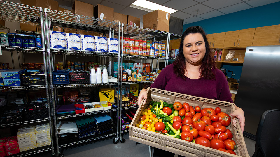 Morgan Smith shows a tote of fresh vegetables available at Husker Pantry in August 2019. [University Communication]