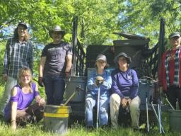 Jennifer Weisbrod (crouched, second from left), John Hay (third from left), and volunteers stand in front of the truck that was used to assist the removal of trash in the creek. 